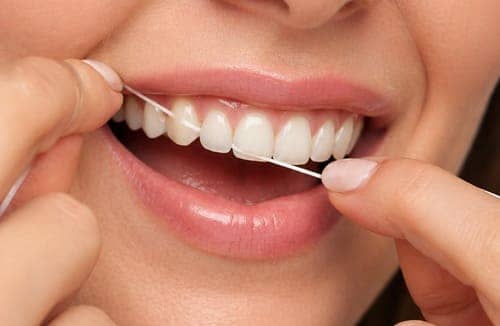 Nahaufnahme einer Frau wie sie ihre Zahnseide nutzt