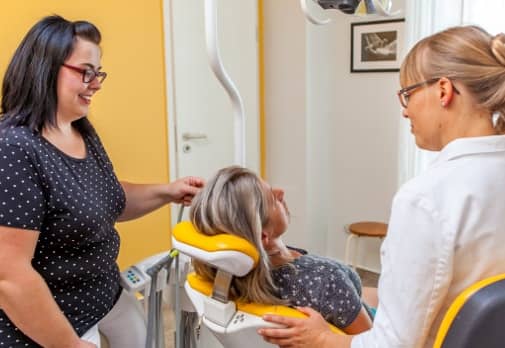 Eine Patientin wir fürsorglich von der Zahnärztin und der Zahnarzthelferin betreut