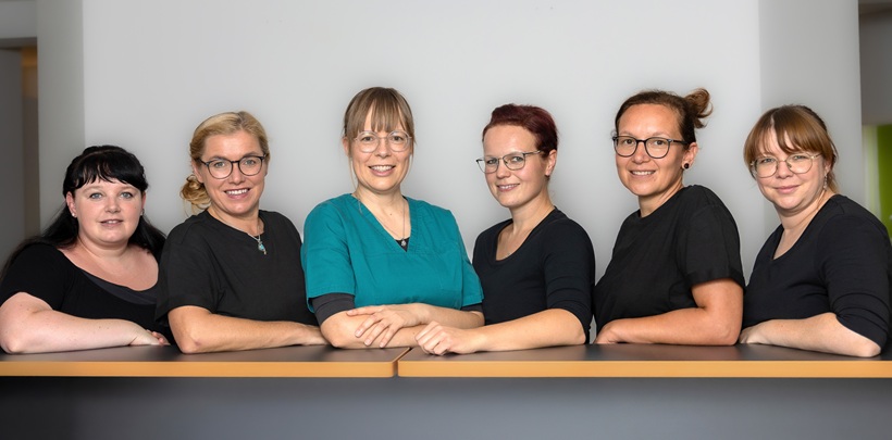Das Team der Zahnarztpraxis steht geschlossen am Tresen